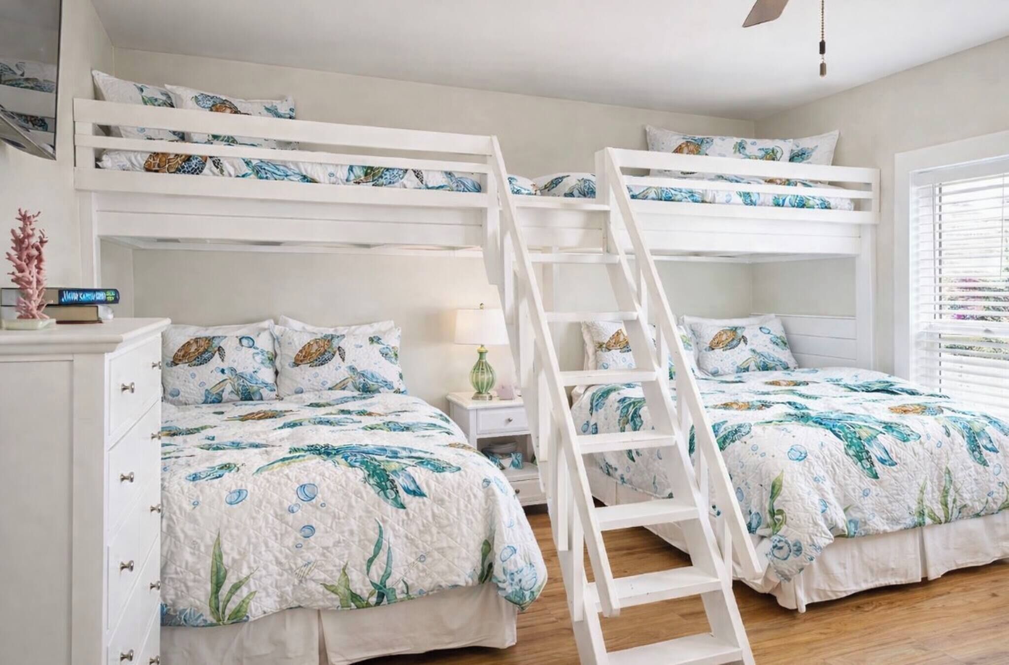 Une chambre avec un lit superposé, une échelle, une table de chevet et une commode.
