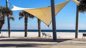 Un paseo marítimo con palmeras, un banco y vista al mar.