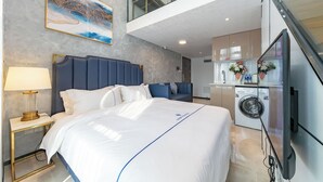 A modern hotel room with a large bed, a desk with a lamp, a washing machine, and a TV. - Hengbang Times Huaqiang North Store (Shenzhen)