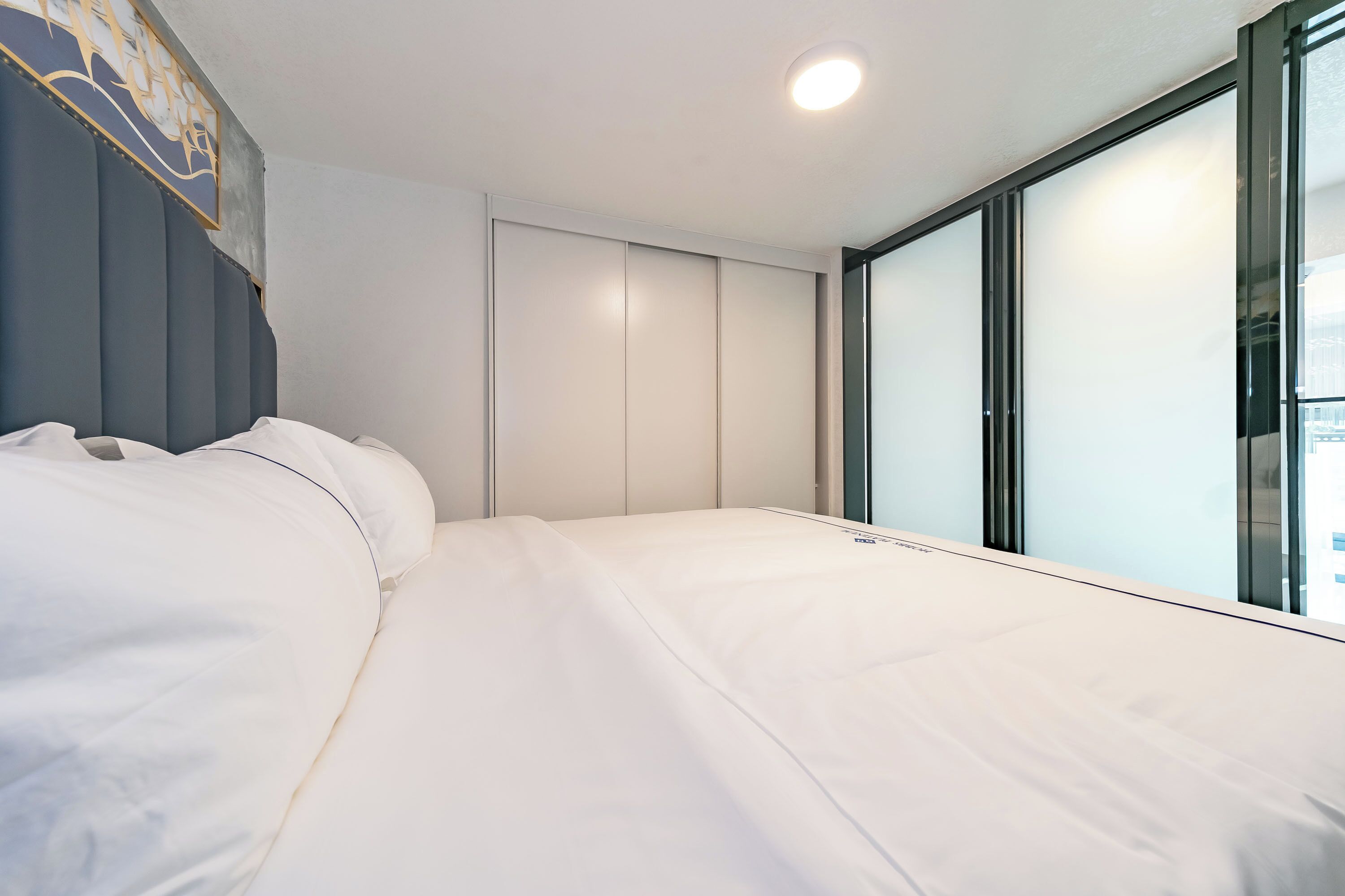 A modern hotel room with a large bed, a wardrobe, and a window with a city view.