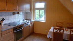 A kitchen with wooden cabinets, a countertop, a sink, an oven, and a window.
