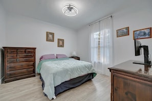 A bedroom with a bed, wooden dresser, nightstand, and ceiling fan. - St. Petersburg Vacation Home (St. Petersburg)