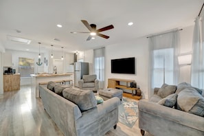A modern living room with a sofa set, a television, and a ceiling fan.