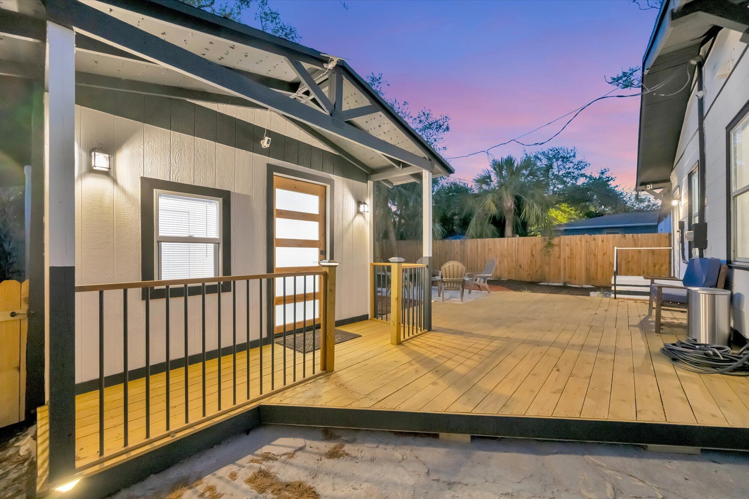 A house with a wooden deck, a covered porch, and a fenced backyard.