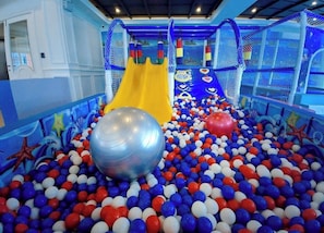 An indoor play area with a ball pit, a yellow slide, and netted play structures. - sevenseas cote  condo stay studio near walkable beach (Tambon Na Chom Thian)