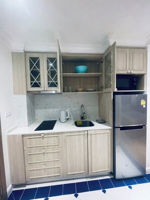 A kitchen with wooden cabinets, a sink, a stove, and a refrigerator. - sevenseas cote  condo stay studio near walkable beach (Tambon Na Chom Thian)