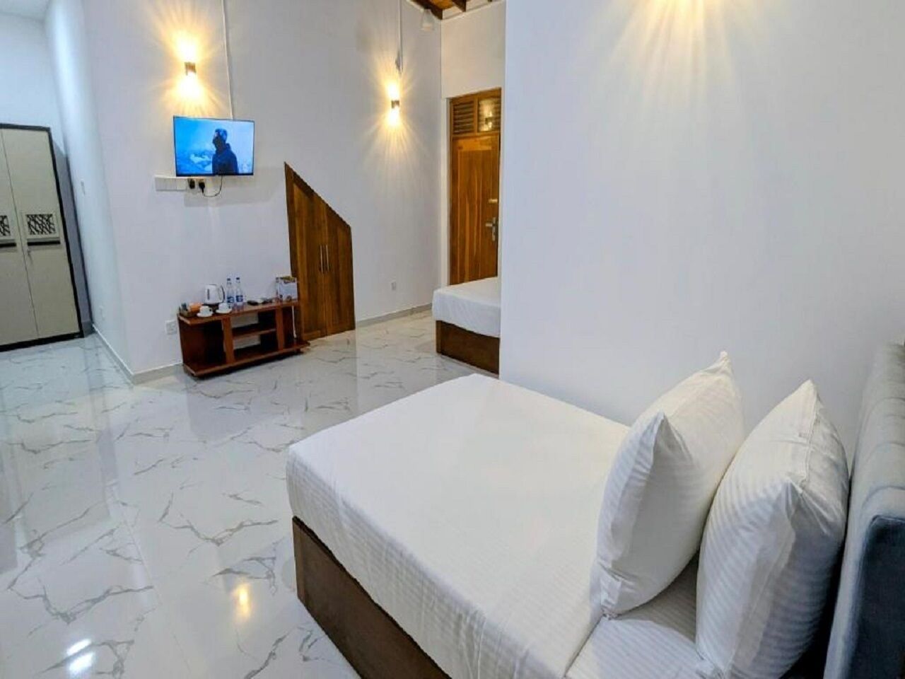A bedroom with a bed, a TV, a wooden cabinet, and a door.