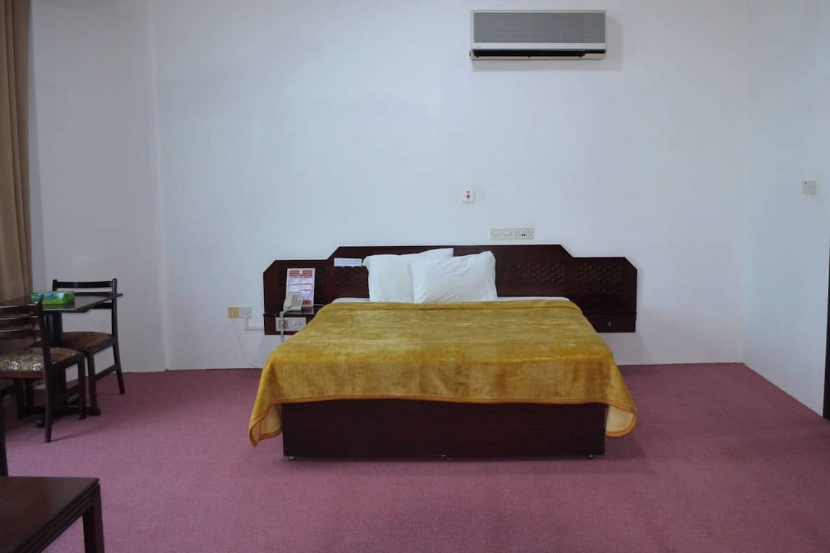 Une chambre d’hôtel équipée d’un lit, d’un bureau, d’une chaise, d’un climatiseur et d’une porte.