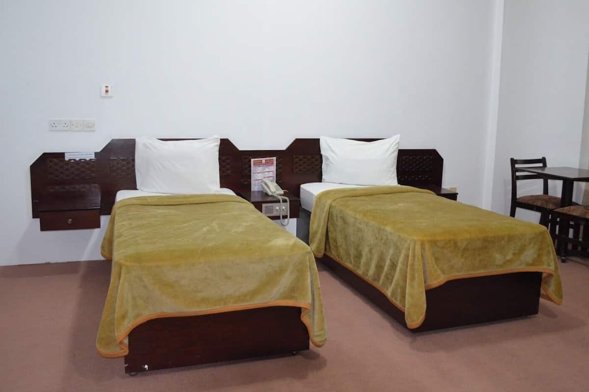 Une chambre d’hôtel avec deux lits, un bureau, une chaise et un téléphone.