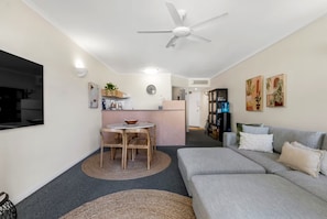 A compact living space with a kitchenette, a dining area, and a seating area with a sofa and chairs. - Juliette’s View | Boutique Stay Near Esplanade (Cairns City)