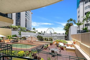 A rooftop pool area with outdoor seating, a Ferris wheel in the background, and surrounding greenery. - Juliette’s View | Boutique Stay Near Esplanade (Cairns City)
