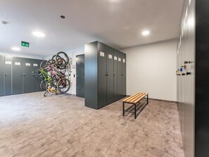 Ein Umkleideraum mit mehreren Schließfächern, einer Bank und einem Fahrradständer mit verschiedenen Fahrrädern.