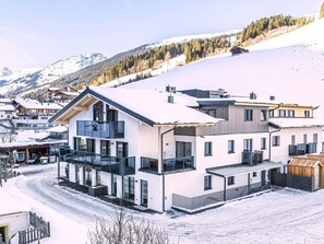 Ein modernes, mehrstöckiges Gebäude mit Balkonen in einer verschneiten Berglandschaft.