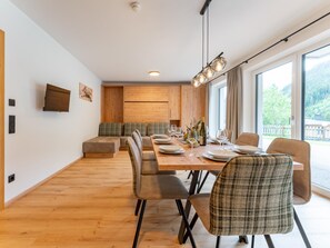 A modern dining area with a wooden table set for four, flanked by cushioned seating. - Ski in-ski out with a large wellness area (Hinterglemm)