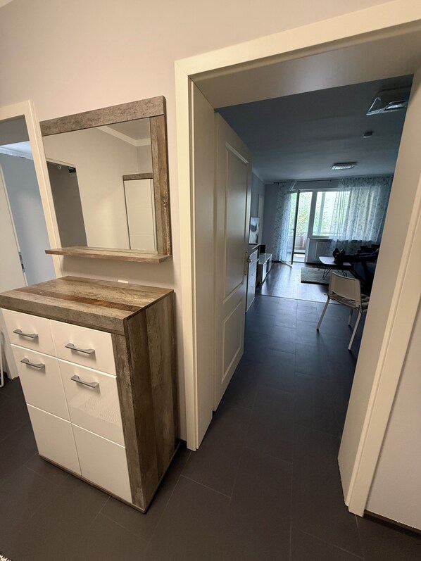 Ein Zimmer mit einem hölzernen Waschtisch, einem Spiegel und einer Tür zu einem Wohnbereich mit einer Couch und einem Tisch.