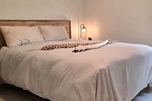 Ein Bett mit Holz-Kopfteil, einem Kissen in Giraffenform und einer Nachttischlampe.