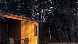 Eine Holzhütte mit Veranda, zwei Stühlen und einem Tisch.