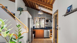 Eine moderne Küche mit Holzbalken, einem Edelstahlkühlschrank und einem Fenster mit Blick auf Grünflächen.