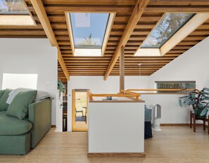 A modern interior with a loft-style ceiling, a green sofa, a small table, and a potted plant.