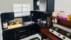 A compact kitchen with a black countertop, a sink, a stove, and a cabinet with dishes.
