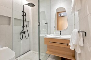 Une salle de bain moderne avec une douche à parois de verre, un meuble-lavabo en bois et un grand miroir.