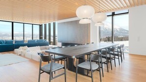 Ein modernes Interieur mit einem großen Esstisch, Stühlen, einer Couch und Blick auf einen Berg.
