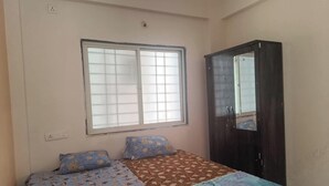 A bedroom with a bed, two pillows, a wardrobe, and a window.