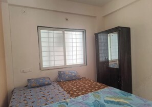 Un dormitorio con cama, dos almohadas, un armario y una ventana.