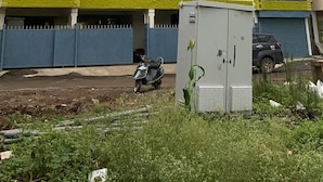 Un immeuble résidentiel à plusieurs étages, doté de balcons, d’une entrée sécurisée et où se trouve un scooter garé.