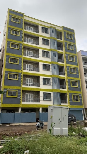 Un edificio residencial de varios pisos con balcones, una entrada con portón y una moto estacionada.