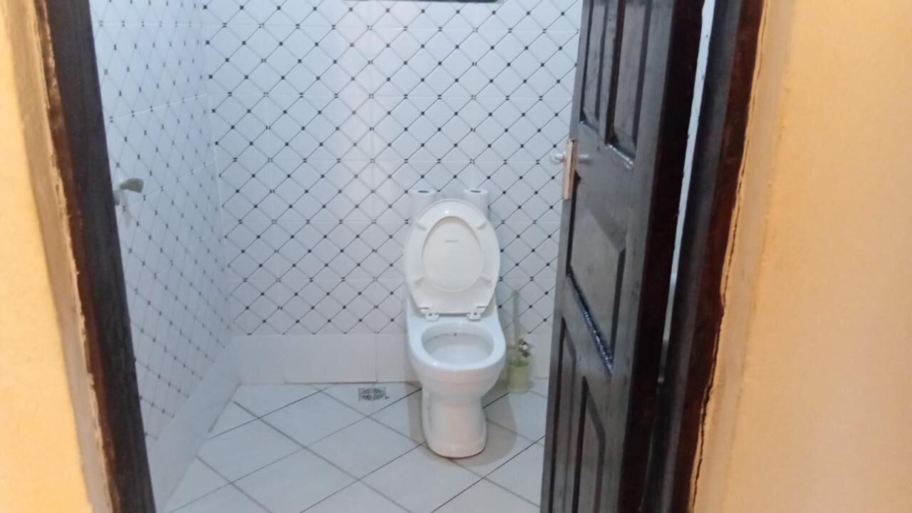 A small, tiled bathroom with a toilet, a shower area, and a door.