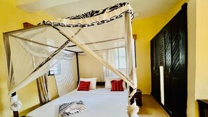 Ein Himmelbett mit Baldachin, einer weißen Bettdecke und roten sowie weißen Kissen.
