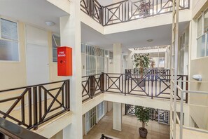 Ein mehrgeschossiges Atrium mit einem Brandmelder, Geländern und Topfpflanzen.