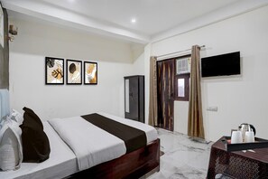 Een hotelkamer met een bed, een televisie, een kast en kunst aan de muur.
