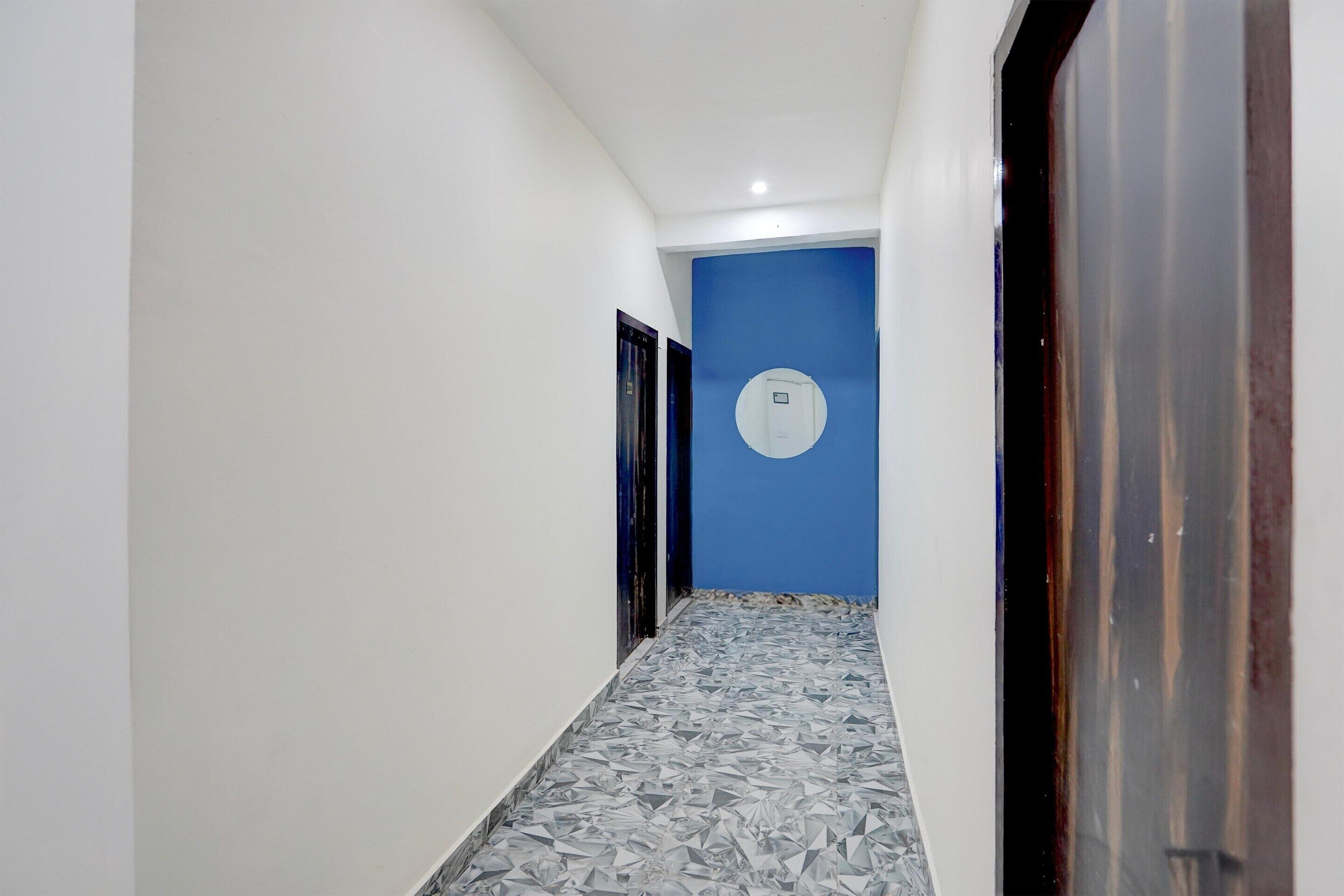 A narrow hallway with a blue accent wall, a tiled floor, and a door with a circular window.