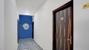 Ein Flur mit blauer Wand, einer Holztür mit einer Nummer und einem Fliesenboden.