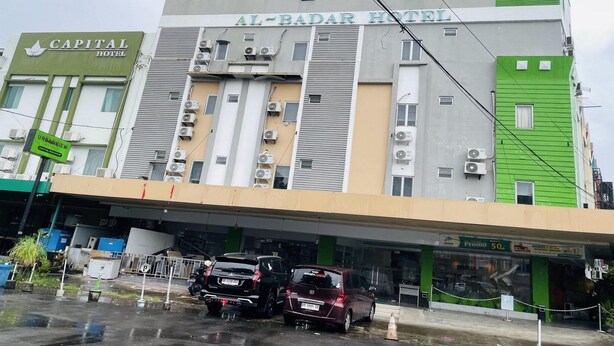 Un hôtel à plusieurs étages, doté de systèmes de climatisation et disposant d’un parking avec des voitures.