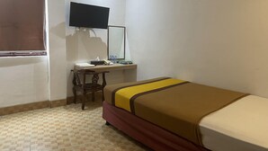 Une pièce comprenant un lit, un bureau, une chaise, une télévision et une fenêtre.
