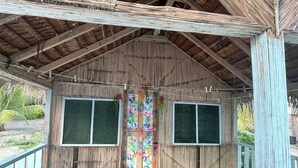 A wooden structure with a thatched roof, two windows, and a wooden deck.