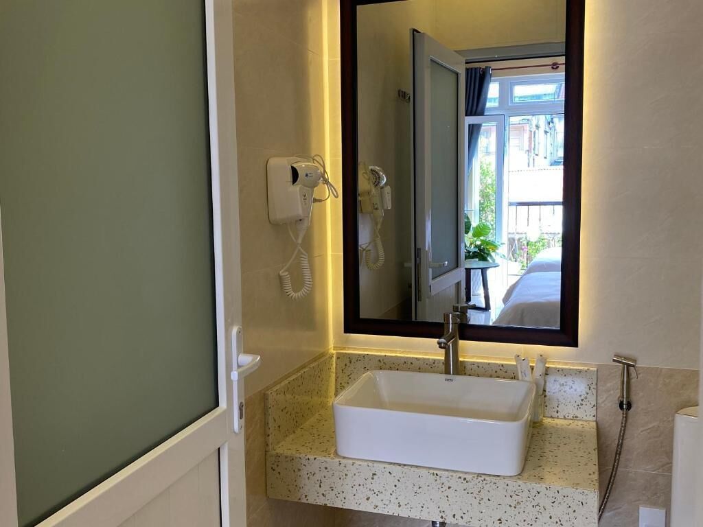 A bathroom with a white sink, a mirror, and a hairdryer mounted on the wall.