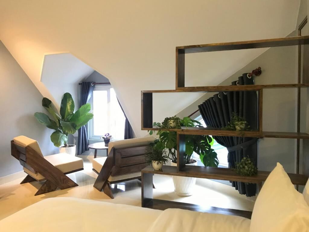 A modern room with a sloped ceiling, a wooden bench, a small table, and a shelving unit with plants.