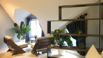 A modern room with a sloped ceiling, a wooden bench, a small table, and a shelving unit with plants.