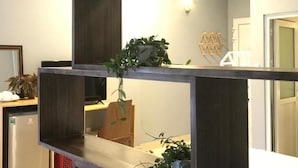 Un interior moderno con estructura de madera oscura, una planta en maceta y una lámpara fijada a la pared.