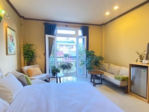 Una habitación de hotel con una cama, un sofá, una mesita y un refrigerador.