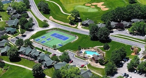 An aerial view of a residential area with houses, a tennis court, and a swimming pool.