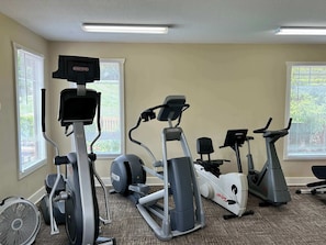 A gym with various exercise equipment including treadmills, an elliptical, and a fan.
