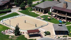 Ein Luftbild eines Hotels mit Tennisplatz, überdachter Sitzgelegenheit und Schwimmbecken.