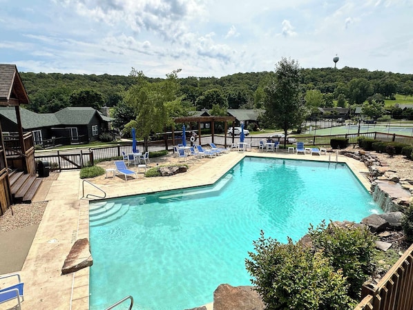 A swimming pool with lounge chairs and a wooden deck.