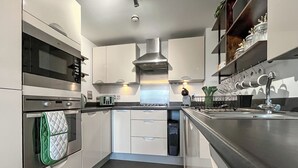 Una cocina moderna con electrodomésticos de acero inoxidable, armarios blancos y un horno empotrado.
