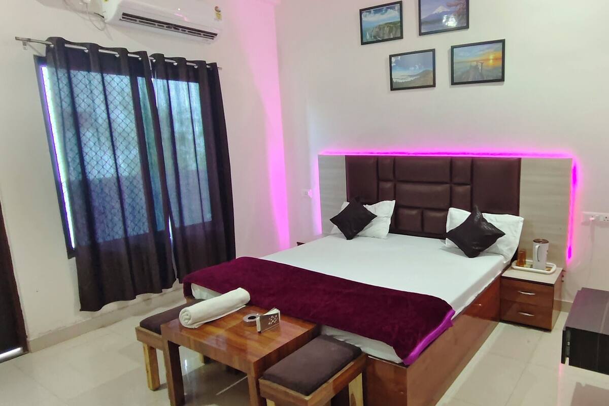 A hotel room with a bed, bedside table, and a window with curtains.